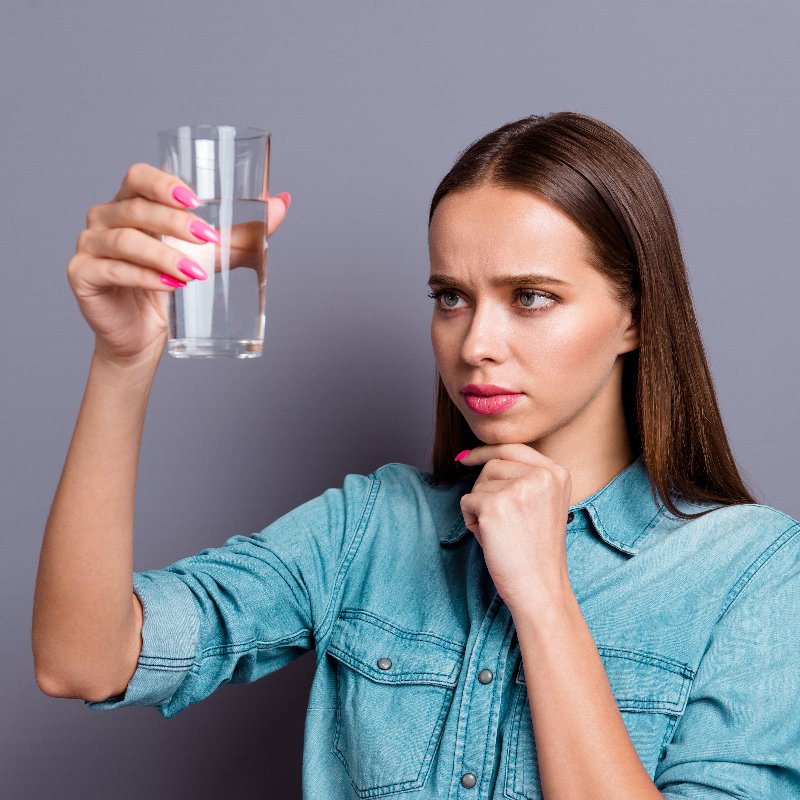young woman examining a glass of water