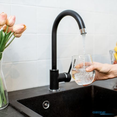 Woman filling glass with tap water for drinking on the kitchen.